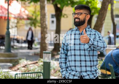 J'aime. Heureux homme barbu indien lève les pouces vers le haut est d'accord avec quelque chose donne une réponse positive recommande la publicité bonne idée rétroaction, célébrant la victoire de succès à l'extérieur. Guy sur la rue de la ville. Banque D'Images