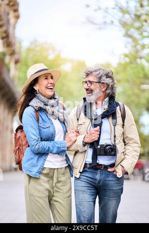 Joyeux couple plus âgé qui s'amuse à se promener en plein air en ville. Les retraités profitent d'une promenade touristique. Banque D'Images