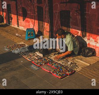Jakarta, Indonésie - 7 mai 2024. le vendeur accroupissant près du mur du long couloir. Banque D'Images