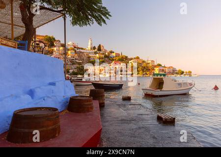 Vue panoramique des maisons colorées et des bateaux dans le port de l'île de Symi, Grèce, au coucher du soleil Banque D'Images