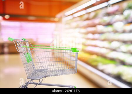 Allée de supermarché avec des légumes frais et des étagères de fruits arrière-plan flou intérieur avec panier vide Banque D'Images