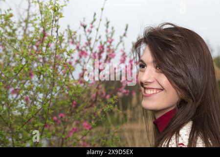 Charmante jeune femme en cardigan blanc. Le tournage a eu lieu dans la ville de printemps dans le parc de Roses Valley. Banque D'Images