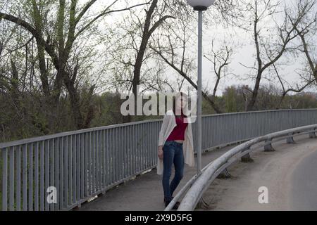 Charmante jeune femme en cardigan blanc. Le tournage a eu lieu dans la ville de printemps près du parc de Roses Valley. Banque D'Images