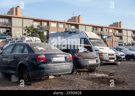 Diverses voitures stationnées devant un immeuble moderne, y compris une voiture abandonnée. Banque D'Images