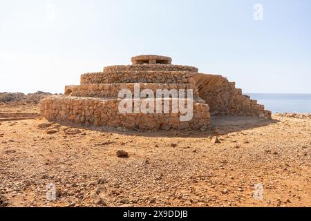 Bunker en pierre reconstruit de la guerre civile espagnole à Punta Nati, sur l'île de Minorque, Espagne. Dans un paysage aride et rocheux avec la mer derrière. Histo Banque D'Images