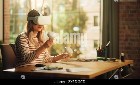 Femme blonde portant un casque VR 3D et utilisant des contrôleurs modernes dans le salon de l'appartement loft. Designer féminin travaillant dans l'application futuriste. Nouvelles technologies et hologramme de réalité augmentée. Banque D'Images