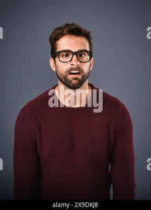 Studio, lunettes et homme au visage drôle, soins oculaires et bien-être avec monture, portrait et lentille pour la vision. Fond gris, sain et produit pour Banque D'Images