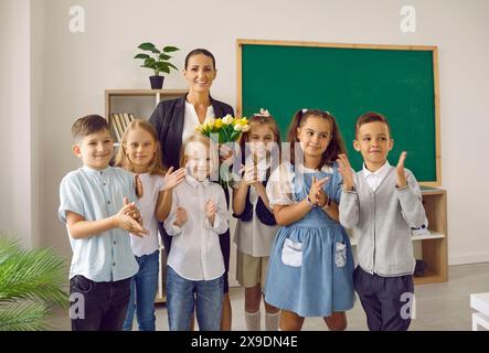 Portrait de groupe d'enfants heureux et de leur professeur avec des fleurs le jour de l'enseignant Banque D'Images