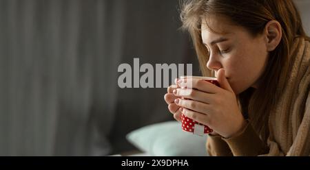 femme malsaine adulte boit du thé chaud de la tasse. Traitement à domicile. Banque D'Images