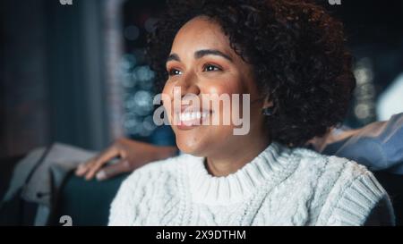 Femme heureuse afro-américaine appréciant le service de streaming de film et riant tout en se relaxant sur le canapé avec son petit ami. Divertissement en ligne moderne pour téléviseur intelligent. Banque D'Images