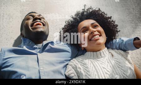 Ci-dessus Portrait de couple multiethnique couché sur le tapis et parlant, rêvant et imaginant. Conjoints exprimant des soins et de l'amour l'un pour l'autre. Concept « Enjoy Time Together ». Banque D'Images