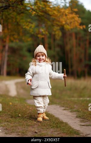 petite fille heureuse souriante marchant à travers la forêt d'automne Banque D'Images