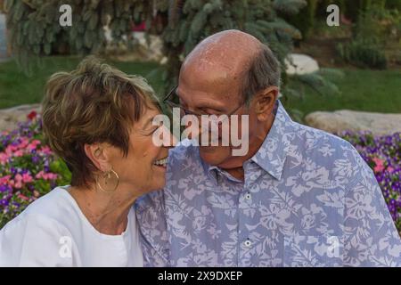 Gros plan d'un joyeux couple âgé riant dans un jardin fleuri Banque D'Images