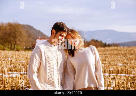 Jeune couple penchant les têtes ensemble, debout dans un champ récolté Banque D'Images