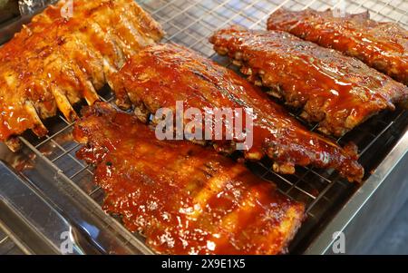 Tas de délicieuses côtes de porc épicées au barbecue fraîchement cuites à vendre sur un marché local à Bangkok, Thaïlande Banque D'Images