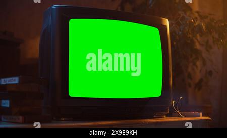 Gros plan d'un téléviseur daté avec écran vert maquette Chroma Key. Nostalgique Retro Nineties concept technologique. Affichage de télévision vintage dans le salon. Banque D'Images