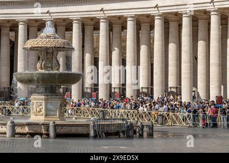 Foules de gens faisant la queue par les colonnes doriques et la fontaine Maderno de la place Saint-Pierre pour entrer dans la basilique Saint-Pierre, Cité du Vatican Banque D'Images