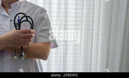 Femme médecin ou cardiologue en uniforme blanc avec stéthoscope à la main. Clinique médicale de cardiologie, traitement cardiaque, concept de soins de santé Banque D'Images