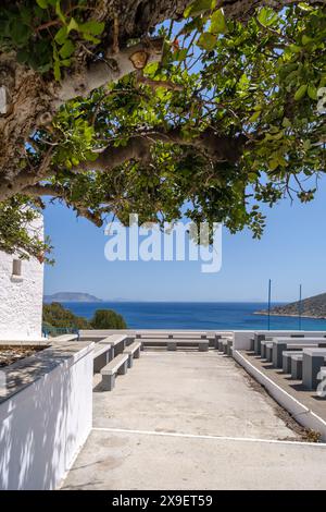 Vue sur les bancs et les tables de l'église Agia Theodoti surplombant la belle plage turquoise d'iOS Grèce Banque D'Images