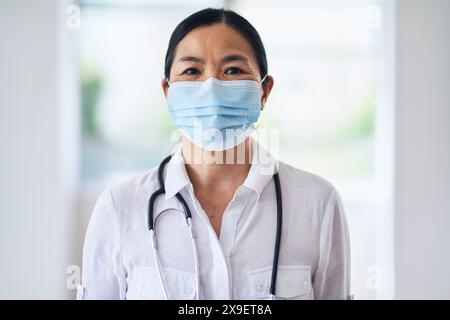 Médecin féminin confiant portant un masque facial dans un cadre hospitalier Banque D'Images