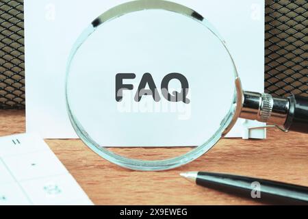 FAQ concept à travers une loupe sur une feuille blanche Banque D'Images
