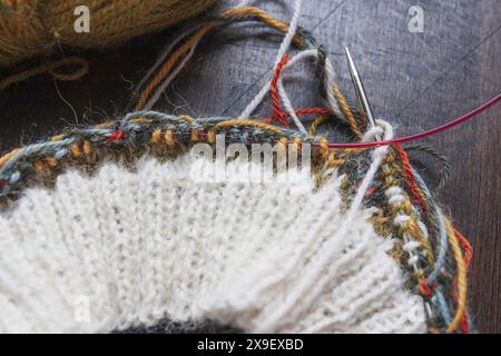 Photographie rapprochée du projet de tricot Fair Isle sur les aiguilles en cours avec un fil d'alpaga blanc fin et coloré Banque D'Images