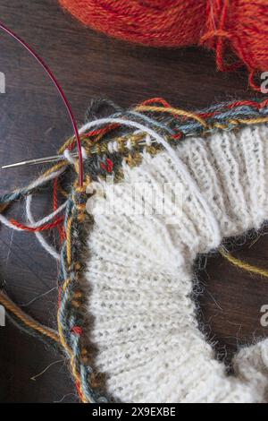 Photographie rapprochée du projet de tricot Fair Isle sur les aiguilles en cours avec un fil d'alpaga blanc fin et coloré Banque D'Images