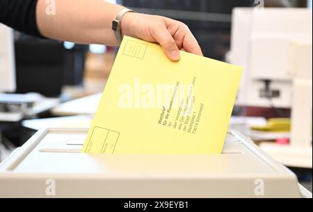 Schorndorf, Allemagne. 31 mai 2024. Une lettre de vote avec un bulletin de vote pour l'élection municipale est placée dans une urne à un bureau de vote de l'hôtel de ville pour le vote par correspondance. Crédit : Bernd Weißbrod/dpa/Alamy Live News Banque D'Images