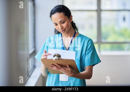 Infirmière spécialisée examinant les dossiers des patients sur le presse-papiers à l'hôpital Banque D'Images