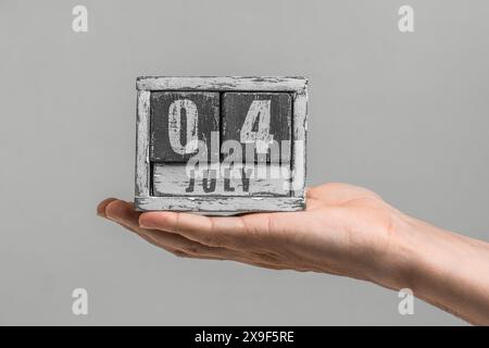 La date est juillet 04. Calendrier en bois à la main sur fond gris Banque D'Images