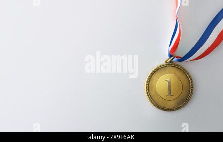 Médaille en métal doré avec numéro un gravé et ruban de couleurs bleu blanc et rouge isolé sur fond blanc. Vue de dessus. Banque D'Images