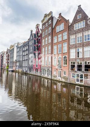 Les maisons colorées, charmantes et minces en pain d'épice de Damrak photographiées sous un ciel nuageux à Amsterdam, aux pays-Bas, le 27 mai 2024. Banque D'Images
