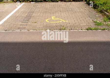 Place de parking avec symbole de fauteuil roulant. Ombre au premier plan. Parking réservé aux personnes handicapées. Concept de responsabilité sociale, de bienveillance, de respect Banque D'Images