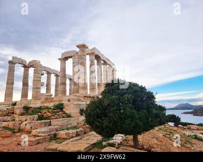 37 km au sud d'Athènes, le temple grec Poséidon se trouve le long de la péninsule Attique. Il est visible par tous les marins qui le traversent et sert de phare pour les Athéniens en mer. Le temple près de l’océan était un endroit approprié pour Poséidon qui est le Dieu de la mer et des tempêtes, et l’un des dieux grecs les plus mauvais, les plus mauvais et les plus gourmands. Le temple a été construit en 444 av. J.-C. et est un endroit populaire pour attraper un coucher de soleil, que vous pouvez regarder à travers ses anciens piliers tandis que le soleil plonge dans la mer Égée. Grèce. Banque D'Images