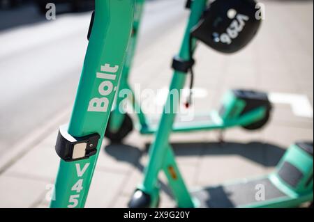 Rangées de scooters électriques verts garés sur un trottoir de la ville. Véhicules de transport personnel urbain à louer. Lituanie Vilnius Banque D'Images