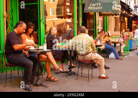 De petits groupes de personnes profitent d'une chaude soirée d'été en sirotant un café en plein air dans un café du Greenwich Village de New York Banque D'Images