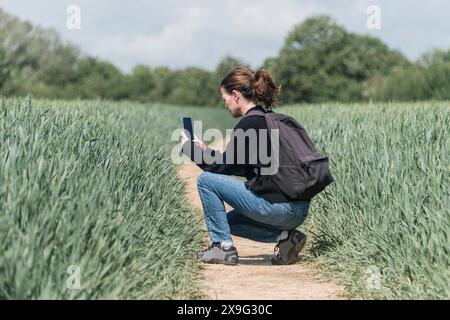 femme adulte moyenne prenant des photos sur son smartphone de cultures poussant dans un champ Banque D'Images