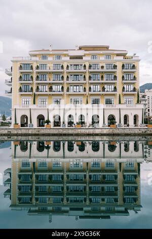 Regent Hotel sur le rivage se reflète dans la mer contre un ciel nuageux. Porto, Monténégro Banque D'Images