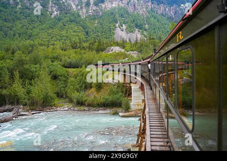 Train à voie étroite de la White Pass and Yukon route sur un vieux pont à chevalets dans les montagnes de l'Alaska entre Skagway et le Canada Banque D'Images