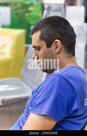 jeune homme attendant sur une chaise son tour dans un magasin Banque D'Images