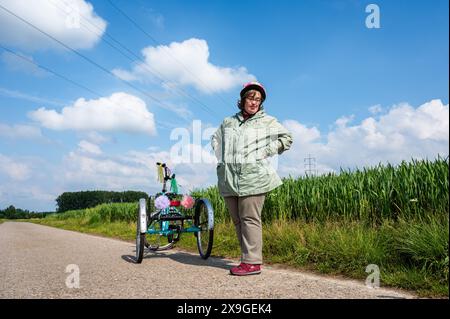 41 ans femme avec le syndrome de Down debout à côté de son tricycle dans les champs autour de Tienen, Flandre, Belgique Banque D'Images