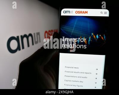 Personne tenant un smartphone avec le site de la société autrichienne d'électronique AMS OSRAM AG devant le logo. Concentrez-vous sur le centre de l'écran du téléphone. Banque D'Images