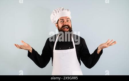 Culinaire professionnel. Gros plan portrait d'heureux chef masculin, cuisinier ou boulanger en uniforme, chapeau et tablier. Cuisson, préparation des aliments. Bel homme barbu i Banque D'Images