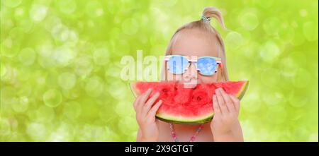 close-up happy cool tendance hipster blonde fille dans des lunettes de soleil manger la pastèque rouge mûre, tranche juteuse dans les mains enfant, tout-petit, souriant joyeusement, Banque D'Images