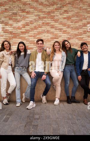 Amis heureux multiraciaux posant pour la photo regardant la caméra joyeuse. Portrait de groupe souriant les gens Banque D'Images