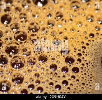 bulles de mousse texturées avec effet bokeh sur la surface de la tasse à café chaude Banque D'Images