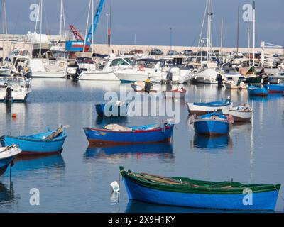 Plusieurs bateaux colorés se trouvent tranquillement dans l'eau du port, la ville de Bari sur la Méditerranée avec des bâtiments historiques, de petits bateaux dans le port Banque D'Images