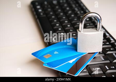 Un cadenas sur une paire de cartes de crédit à côté d'un clavier d'ordinateur sur un fond blanc avec espace de copie Banque D'Images