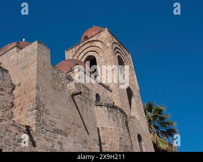 Bâtiment historique de l'église avec des tours rondes, flanqué de palmiers, sous un ciel bleu clair, palerme en sicile avec une impressionnante cathédrale, monuments Banque D'Images