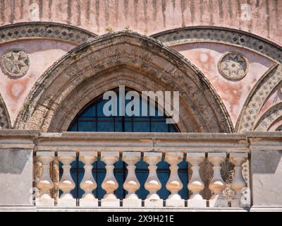 Une fenêtre voûtée avec des ornements en pierre ornés sur un bâtiment historique rose, palerme en sicile avec une impressionnante cathédrale, des monuments et des maisons anciennes Banque D'Images